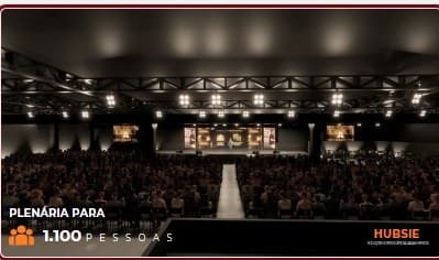 Render 3D da plenária com palco iluminado e telões laterais.